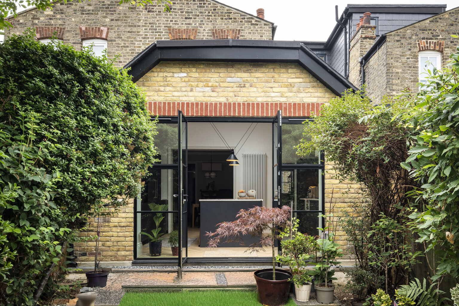 Rear view of an Edwardian terrace on Park Avenue with new brick extension and steel-framed garden doors.