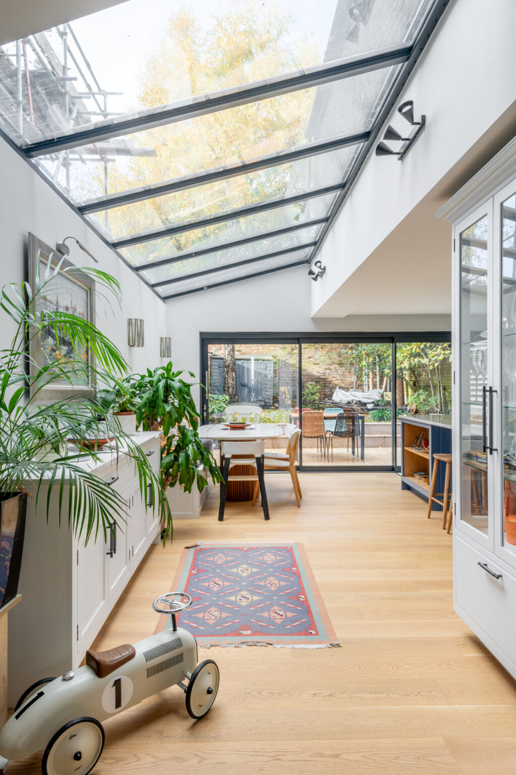Modern rear extension with frameless glass skylight and sliding doors opening to London garden