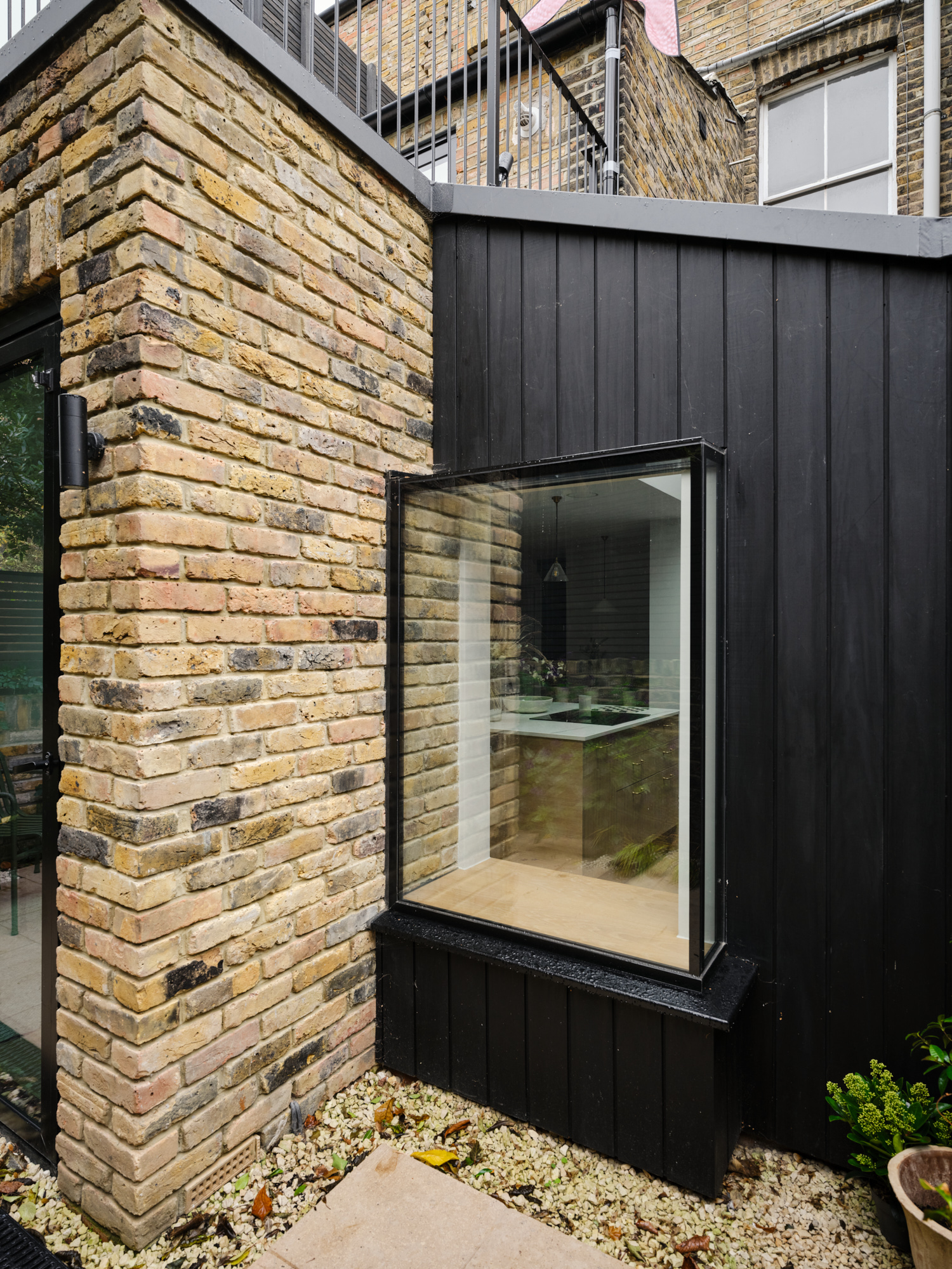 Rear extension exterior with black timber cladding, brick facade, and corner window