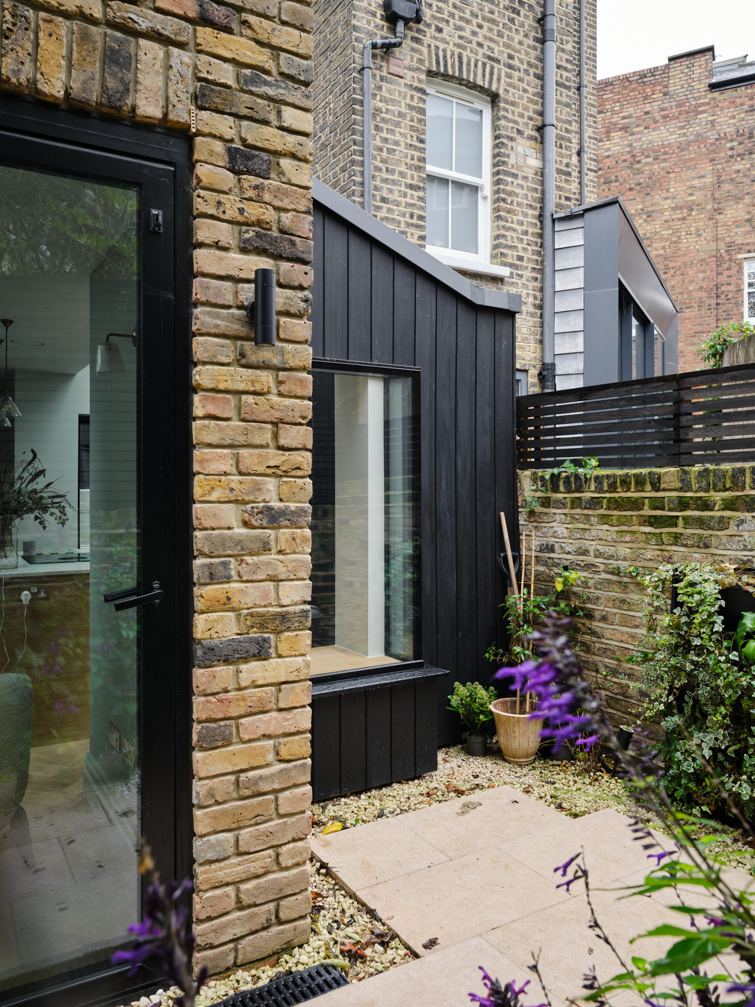 Rear extension exterior with black timber cladding, garden planting, and glazing