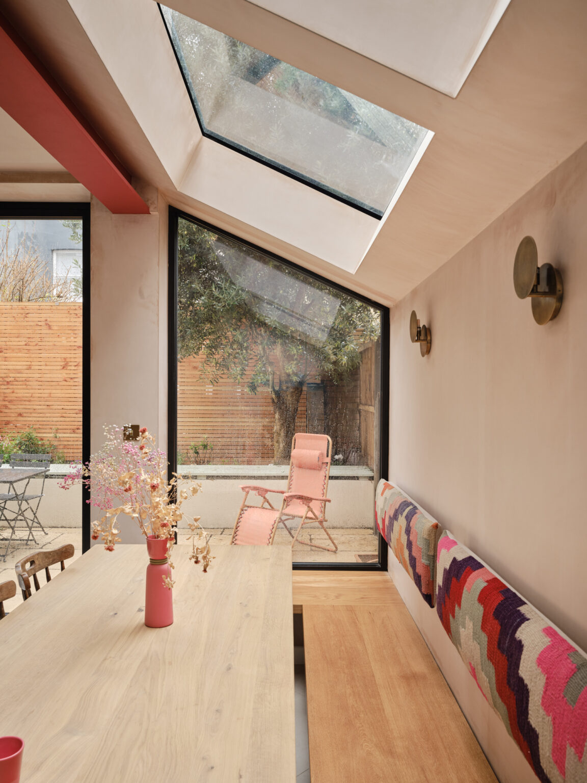 Kitchen window seat with timber bench, patterned textile backrest, and garden view