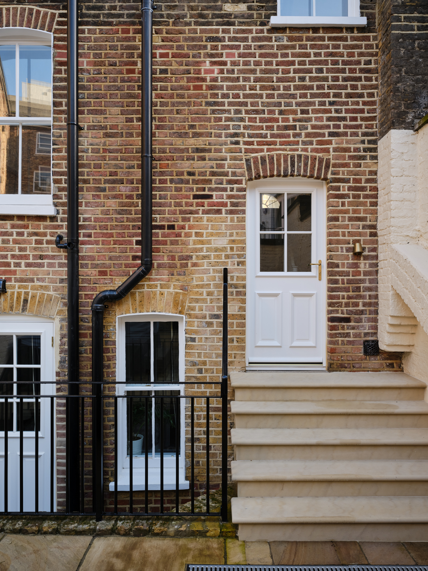 Georgian red brick rear elevation with arched windows and stone steps in Marylebone